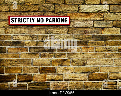 Eine "Streng No Parking" Mitteilung über eine Mauer. Die Zeichen hat einen roten Rahmen mit schwarzer Schrift auf weißem. Stockfoto