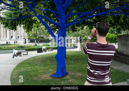 London, UK. 27. Juni 2013. Festival-Gärten, City of London. Menschen interagieren Sie mit einer der Bäume, die als Teil der blauen Bäume in London Kunstinstallation blau gemalt. Nächstenliebe Bäume für Städte gemeinsam mit internationalen Künstler, Konstantin Dimopoulos, kam mit dem Blue Tree-Konzept. Die Idee des Projekts ist es, Menschen zu stoppen und beachten Sie die Bäume im städtischen Umfeld. Wenn Stadtbevölkerung wächst, verringert sich die Anzahl der Bäume in der Stadt. Aber viele Menschen heute um zu betrachten, berühren und Foto eines der blauen Bäume gestoppt. Bildnachweis: Allsorts Stock Foto/Alamy Live-Nachrichten Stockfoto