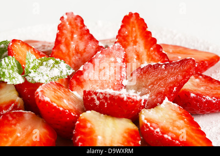 Halbierte Erdbeeren mit Puderzucker bestreut Stockfoto