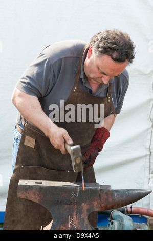 Ein Schmied Hämmern rote Roheisen auf einem Amboss während eines Wettkampfes an der Royal Cornwall Show 2013 Stockfoto