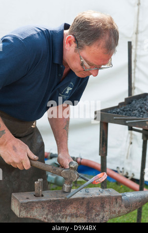 Ein Schmied Hämmern rote Roheisen auf einem Amboss während eines Wettkampfes an der Royal Cornwall Show 2013 Stockfoto