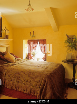 Doppelbett mit Fransen Bettdecke in gelben Land Schlafzimmer mit schrägen Decke Stockfoto