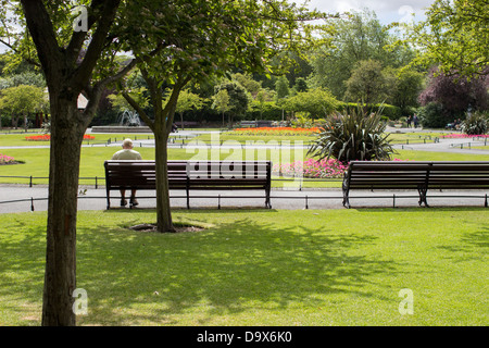 Älterer Mann sitzt auf einer Bank in einem Park. Stockfoto