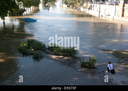 Touristen sitzen betrachten der abklingenden Hochwasser am platzen Ufer der Donau, Budapest, Ungarn Stockfoto
