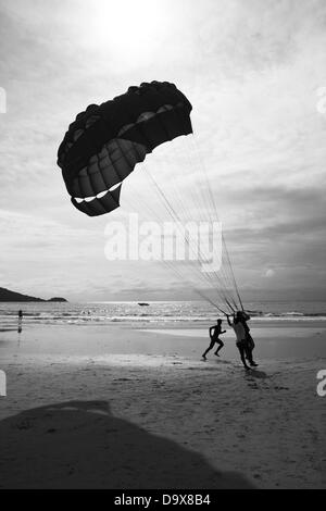 PATONG BEACH, PHUKET, THAILAND, 14. August 2011: Verkaeufers Parasail jagt ein Kunde über den Boden am Patong Beach. Stockfoto