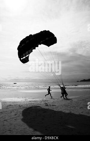 PATONG BEACH, PHUKET, THAILAND, 14. August 2011: Verkaeufers Parasail jagt ein Kunde über den Boden am Patong Beach. Stockfoto