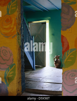 Rustikale Wände gemalt mit floralem Motiv auf beiden Seiten des Einganges in grüne Hütte Halle mit blauen Treppe und Steinplatte Stock Stockfoto