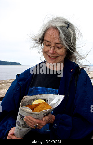 Glückliche Kundin riesige Bestellung Fish &amp; Chips in Zeitung Kegel Entdeckung Fishing Pier Lebensmittel Konzession stehen Stockfoto