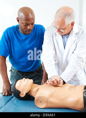 Reife Arzt einer Erwachsene Studenten beizubringen, CPR, verwenden eines Dummys durchführen. Stockfoto