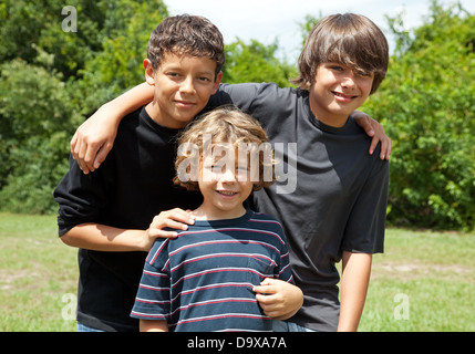 Drei entzückenden jungen, zwei Jugendliche Freunde und einen kleinen Bruder Lächeln auf den Lippen. Vielfalt. Die beiden Brüder sind Rennen gemischt. Stockfoto