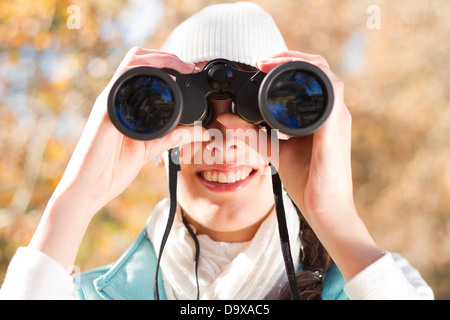 junge Frau mit dem Fernglas im herbstlichen Wald Stockfoto