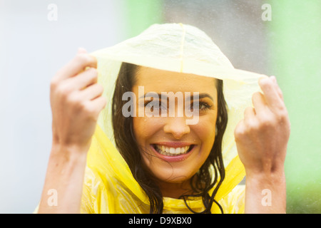 glückliche junge Frau im Poncho im Regen Stockfoto