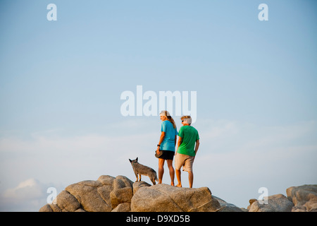 Paar mit Hund wandern am Strand rockt Stockfoto