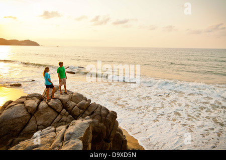 Paar mit Hund wandern am Strand rockt Stockfoto