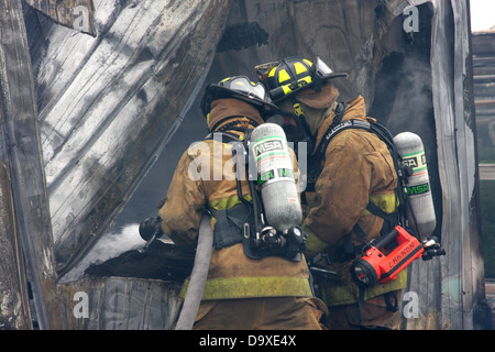 Zwei Feuerwehrleute setzen, ein Feuer mit einem Wasserschlauch Stockfoto