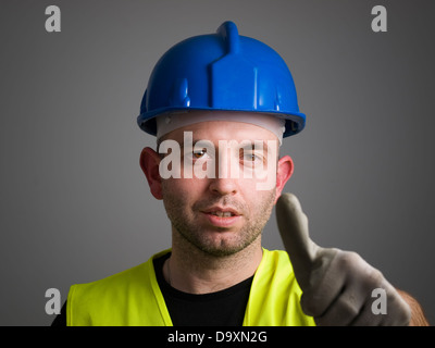 Arbeiter, die positive Emotionen mit ok-Symbol. Der Arbeitnehmer wird auf dunklem Hintergrund isoliert. Stockfoto