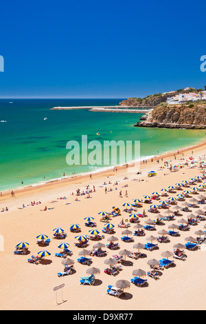 Urlauber zum Sonnenbaden unter Sonnenschirmen auf dem sandigen Strand Praia Túnel Albufeira Strand Algarve Portugal EU Europa Stockfoto