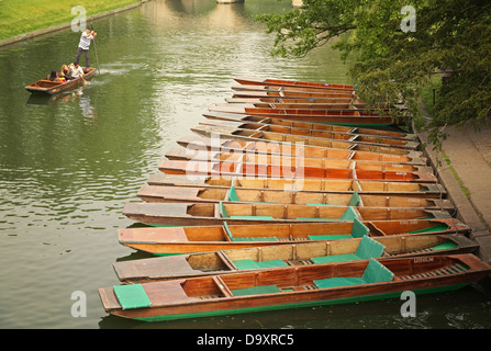 Eine Gruppe von Menschen, vorbei an einer Reihe von leeren Punts Stechkahn fahren auf dem Fluss Cam in Cambridge. Stockfoto