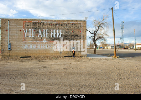 Teenager-Mädchen auf Skateboard mit OBEY Mütze neben Gebäude mit Worten gemalt sind SIE hier an der Wand, Green River, Utah, USA Stockfoto