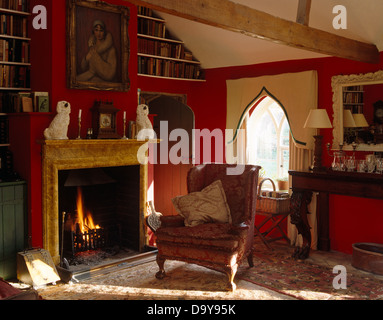 Sessel neben Marmorkamin mit Staffordshire China Hunde im roten Land Wohnzimmer mit Lambrequin Profilkranz auf Fenster Stockfoto