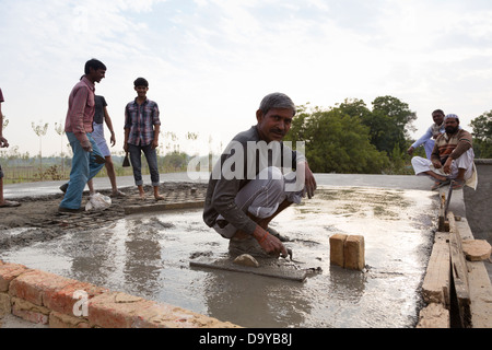 Indien, Uttar Pradesh, Aligarh, Dorfbewohner schwimmenden Zement auf einem Dorf Hausdach Stockfoto