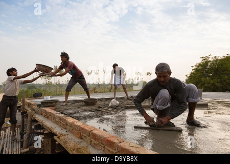 Indien, Uttar Pradesh, Aligarh, Dorfbewohner schwimmenden Zement auf einem Dorf Hausdach Stockfoto