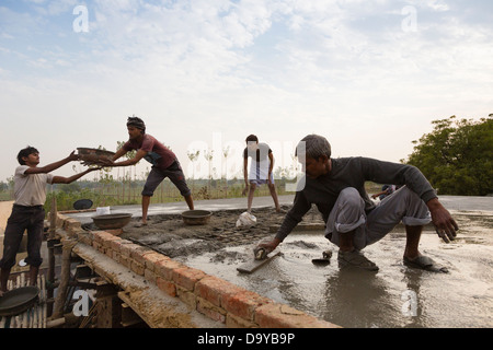 Indien, Uttar Pradesh, Aligarh, Dorfbewohner schwimmenden Zement auf einem Dorf Hausdach Stockfoto