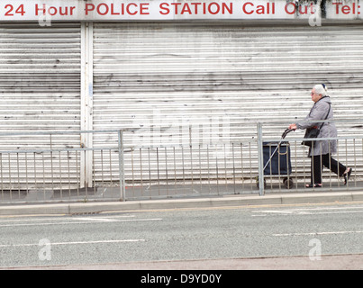 Eine Frau vorbei gehen eine Reihe von geschlossen Geschäfte im Stretford, Manchester, England, Großbritannien Stockfoto