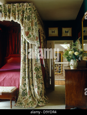 Land-Schlafzimmer mit Himmelbett mit floral Gardinen und Magenta Bettdecke Stockfoto