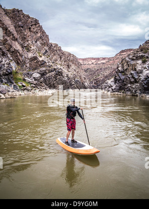 Ein Mann Stand up Paddle boarding auf einem Fluss. Stockfoto