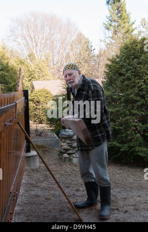 Alter Mann mit Hut Kufi schließen das Tor seines Hauses Stockfoto