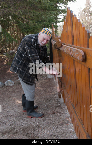 Alter Mann mit einem Kufi Hut und seinem Tor seines Hauses zu reparieren-tool Stockfoto