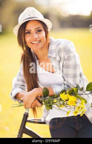 attraktive junge Frau mit Blumen posiert neben einem Fahrrad im freien Stockfoto