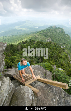 Eine Frau klettert eine Leiter in Großvater Mountain State Park, Linville, North Carolina. Stockfoto