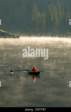 Eine Frau, die ein Scull Rudern Boot einen nebligen Morgen in der Nähe von Creede, Colorado. Stockfoto