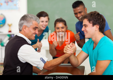 freundlichen mittleren Alter Lehrer Armdrücken mit High-School-Schüler im Klassenzimmer während der Pause Stockfoto