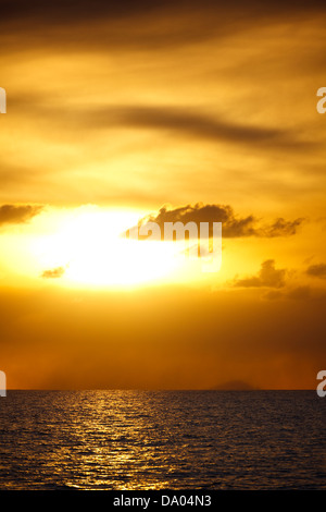 Goldener Sonnenuntergang nach einem Montserrat Vulkanausbruch von Antigua, die Insel Redonda am Horizont gesehen. Stockfoto