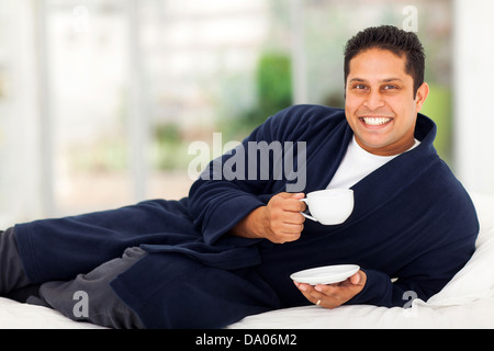 glücklich indischer Mann im Schlafanzug und trinken Kaffee am Bett Stockfoto