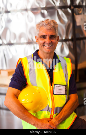 Porträt von senior Versand Unternehmen Arbeitnehmer hält seinen Helm im Lager Stockfoto