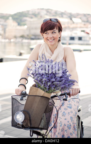 Frauen mit dem Retro-Fahrrad mit Lavendelblüten in Korb Stockfoto
