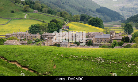 Das Dorf von Muker, Swaledale, umgeben von traditionellen Mähwiesen. Kisdon Schlucht hinter dem Dorf gezeigt. Stockfoto