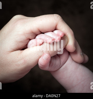 Ein Bild gegen schwarze Babys Hand eines Erwachsenen Daumen Stockfoto