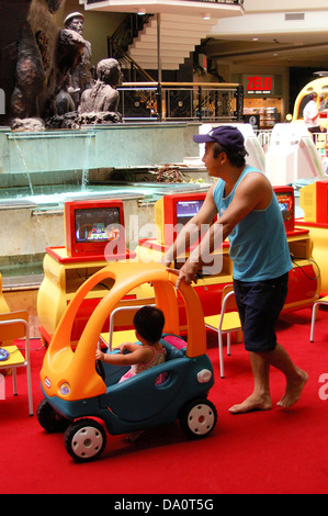 Vater helfen, Kleinkind, ein Spielzeugauto in paly Haus in einem Einkaufszentrum zu fahren Stockfoto