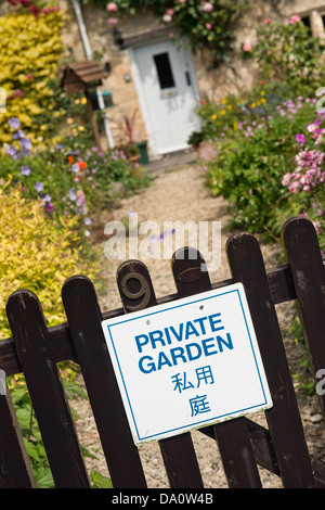 Ein Schild deklarieren "Privatgarten" in Englisch und Japanisch auf dem Tor von einem hübschen Häuschen in Bibury, Gloucestershire, UK Stockfoto