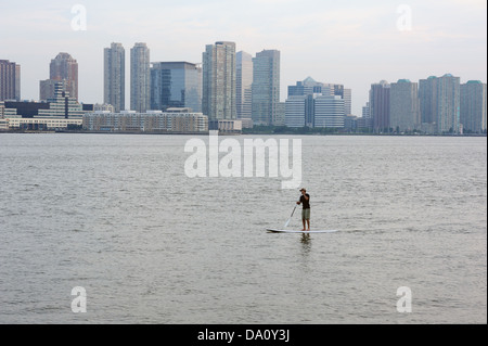 Ein Mann, Paddeln auf dem Hudson River in New York Hafen. Jersey City ist im Hintergrund. Stockfoto