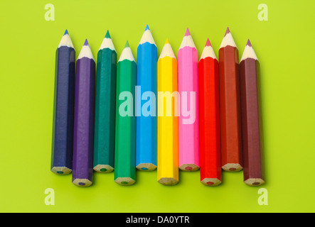 Kleine Stifte hintereinander in Regenbogenfarben olivgrünen Hintergrund Stockfoto