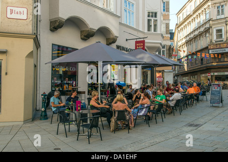 Touristen sitzen in einem Straßencafé in der Linzer Gasse, Salzburg, Österreich Stockfoto