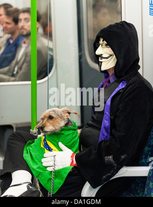 Ein Rohr Personenzug trägt eine Maske und einen kleinen Hund mit der Londoner U-Bahn u-Bahn hält. Stockfoto