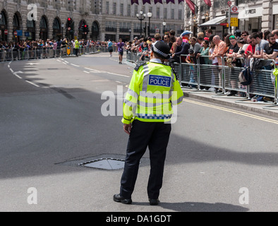 Ein Polizei Polizist steht in der Mitte einer Straße warten auf die London Pride Parade zu beginnen. Stockfoto