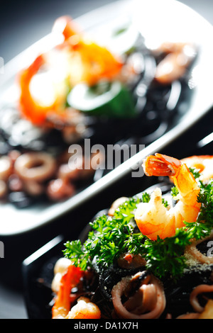 Schwarze Spaghetti mit Meeresfrüchten am schwarzen Tisch Stockfoto